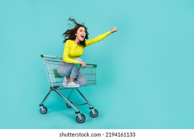 Full size photo of overjoyed carefree girl sit inside market trolley ride empty space isolated on teal color background