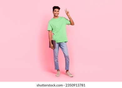 Full size photo of pleasant handsome guy dressed green t-shirt hold laptop showing v-sign symbol isolated on pink color background