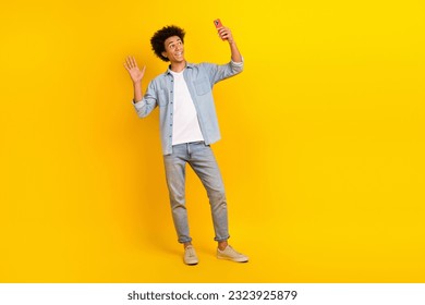 Full size photo of positive friendly person hold smart phone make selfie arm waving hi isolated on yellow color background - Powered by Shutterstock