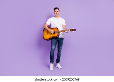 Full size photo of positive joyful cheerful man hold hands play guitar musician isolated on purple color background - Powered by Shutterstock