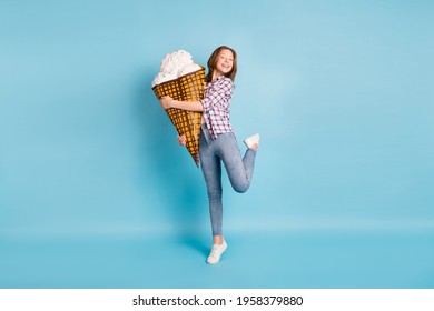 Full Size Photo Of Positive Little Girl Standing On Tip Toe Hold Large Ice Cream Isolated On Blue Color Background