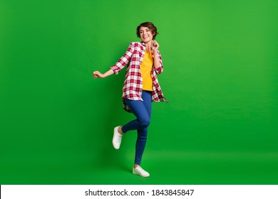 Full size photo of pretty funky lady dancing hands fists wear jeans shirt sneakers isolated on green background - Shutterstock ID 1843845847