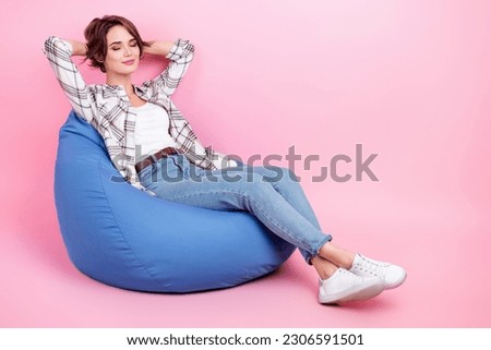 Full size photo of pretty positive girl sit comfort bag closed eyes arms behind head isolated on pink color background