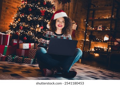 Full size photo of pretty young woman sit carpet floor use laptop christmas festive illumination apartment indoors - Powered by Shutterstock