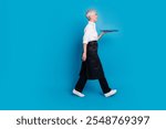 Full size photo of retired female walk profile carry tray barista small coffee shop owner wear waitress uniform isolated on blue background