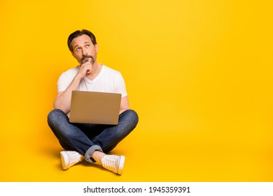 Full size photo of serious minded man sit floor hold laptop look empty space isolated on yellow color background - Powered by Shutterstock