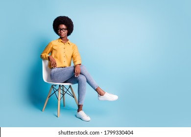 Full size photo of serious smart dark skin girl university college teacher young professor sit chair look good in camera wear stylish clothes isolated over pastel blue color background