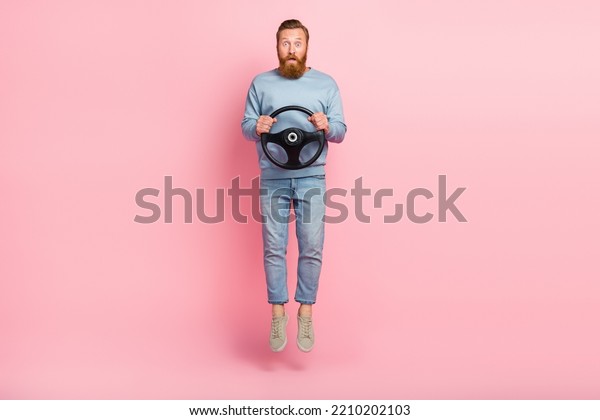 Full size photo of shocked person\
arms hold wheel jumping isolated on pink color\
background