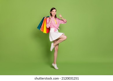 Full size photo of smiling excited girl shopaholic showing thumb-up recommendation isolated on green background - Powered by Shutterstock