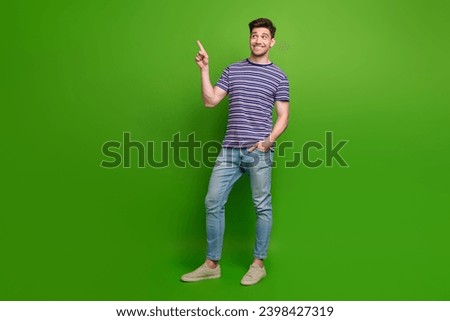 Full size photo of stylish guy dressed striped t-shirt jeans look indicating at sale empty space isolated on green color background