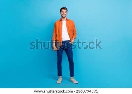 Full size photo of successful positive person put hand pocket hold netbook posing isolated on blue color background
