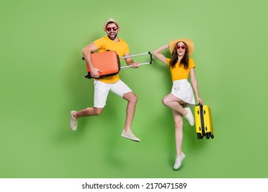 Full Size Photo Of Two Excited Energetic People Jumping Hold Suitcase Isolated On Green Color Background