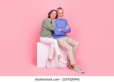 Full size photo of two peaceful idyllic partners sit podium cuddle folded arms isolated on pink color background - Powered by Shutterstock