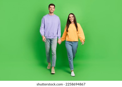 Full size photo of two positive idyllic partners hold arms walking isolated on green color background - Powered by Shutterstock