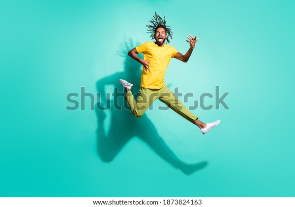 Full size photo of young crazy smiling\
cheerful excited african man jump play invisible guitar isolated on\
teal color background