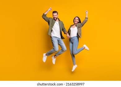 Full size photo of young excited couple energetic jump rejoice victory success yes fists hands isolated over yellow color background - Shutterstock ID 2163258997
