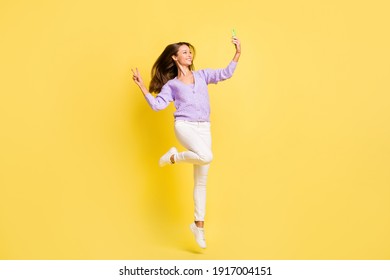 Full size photo of young girl happy positive smile make selfie show peace cool v-sign jump isolated over yellow color background - Shutterstock ID 1917004151