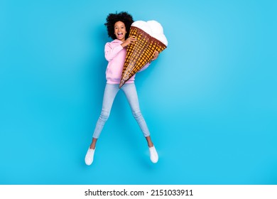 Full Size Photo Of Young Girl Have Fun Jump Energetic Holding Big Ice Cream Isolated Over Blue Color Background