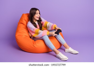 Full size photo of young lovely smiling excited crazy girl playing playstation sit armchair isolated on violet color background