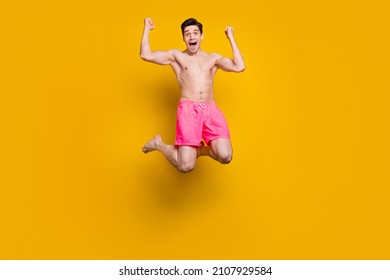 Full size photo of young man happy positive smile rejoice victory success trip swimwear isolated over yellow color background