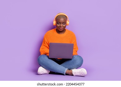 Full size portrait of charming nice girl sit floor listen music use netbook isolated on purple color background