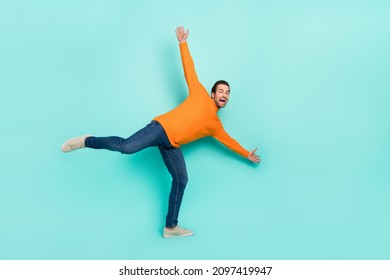 Full Size Portrait Of Cheerful Foolish Man Stand One Leg Raise Arms Rejoice Isolated On Teal Color Background