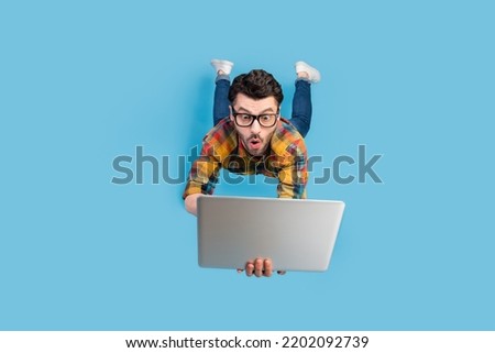 Full size portrait of craze geek man falling hands hold use netbook isolated on blue color background