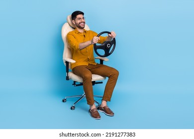 Full Size Portrait Of Excited Funny Person Sit Chair Hands Hold Wheel Isolated On Blue Color Background