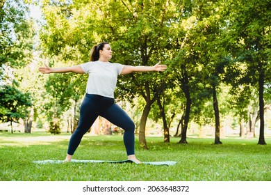 Full size portrait of a fit plump plus-size caucasian woman athlete in sporty outfit standing in yoga position meditating relaxing relaxing on fitness mat. Yoga training outdoors in park. - Powered by Shutterstock