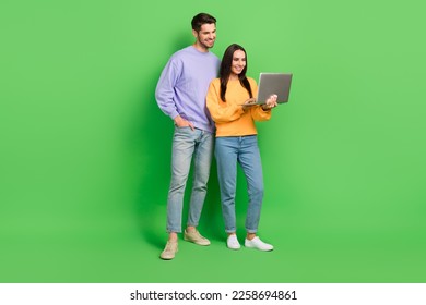 Full size portrait of handsome guy attractive lady hold use wireless netbook isolated on green color background - Powered by Shutterstock