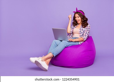 Full Size Portrait Of Lady In Checkered Shirt Denim Jeans Her Brunette Curly Wave Style Stylish Hair She Sit Isolated On Violet Purple Trendy Background Work On Notebook Open Mouth Raised Fist Up