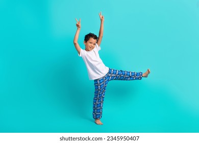 Full size portrait of little excited carefree schoolkid dance arms fingers demonstrate v-sign isolated on aquamarine color background
