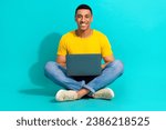 Full size portrait of positive nice person sit floor crossed legs use netbook isolated on aquamarine color background