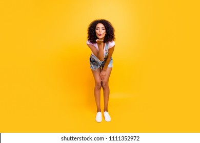 Full size portrait of tempting seductive girl blowing air kiss with pout lips palm at camera isolated on yellow background. Valentine day concept