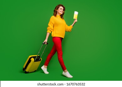 Full Size Profile Photo Of Cheerful Lady Hold Tickets Passport Travel Abroad Rolling Case Go Flight Registration Table Wear Yellow Sweater Red Pants Shoes Isolated Green Color Background