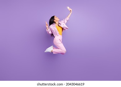 Full size profile photo of funky millennial brunette lady do selfie jump wear jacket jeans sneakers isolated on violet background