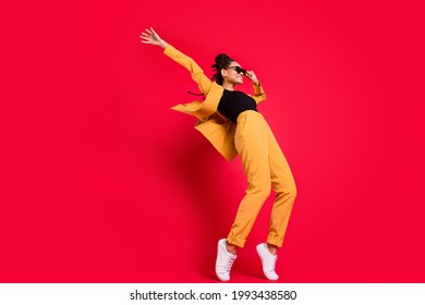 Foto de perfil de tamaño completo de la danza de la dama divertida usa traje amarillo de la ropa de ojos aislado en un fondo de color rojo vívido