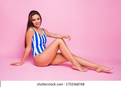 Full size profile photo of ideal figure lady straight hairdo enjoy sun rays sit floor long slim barefoot legs wear white blue striped bodysuit isolated pastel pink color background
