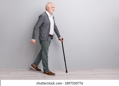 Full size profile photo of old man go with wand wear dark sweater trousers isolated on grey wall - Powered by Shutterstock