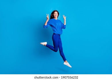 Full size profile photo of optimistic cute lady jump show v-sign wear sweater trousers sneakers isolated on bright background - Shutterstock ID 1907556232