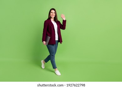 Full Size Profile Photo Of Optimistic Brown Hairdo Lady Go With Laptop Wave Wear Spectacles Red Cardigan Jeans Sneakers Isolated On Green Background