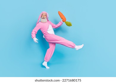 Full size profile photo of positive aged person walk arm hold carrot toy isolated on blue color background