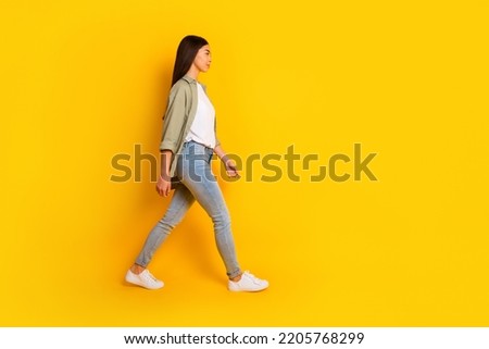 Full size profile photo of pretty charming person look walking empty space isolated on yellow color background