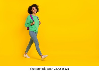 Full size profile portrait of cheerful pretty lady walking empty space isolated on yellow color background - Powered by Shutterstock