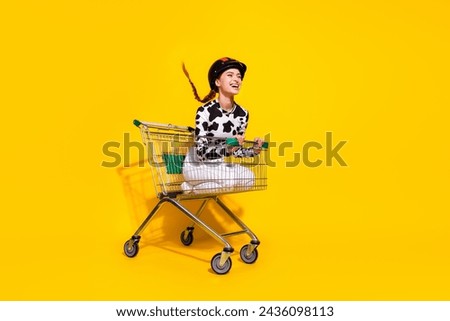 Full size profile portrait of overjoyed girl inside market pushcart ride empty space isolated on yellow color background