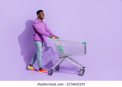 Full size profile portrait of positive person push trolley look empty space isolated on violet color background