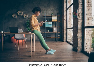 Full Size Profile Side Photo Of Cool Smart Afro American Girl Entrepreneur Use Tablet Work Read Start-up News Wear Yellow Shirt Green Pants Trousers In Office Loft