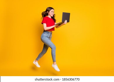 Full Size Profile Side Photo Of Girl Jump Work Laptop Find Sales Run Wear T-shirt Jeans Isolated Yellow Color Background