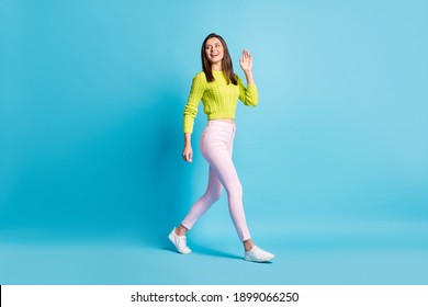 Full Size Profile Side Photo Of Young Woman Smile Go Walk Wave Hand Hello Hi Look Empty Space Isolated Over Blue Color Background