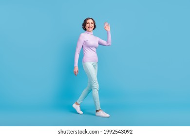 Full Size Profile Side Photo Of Mature Woman Happy Positive Smile Go Walk Wave Hand Hello Isolated Over Blue Color Background